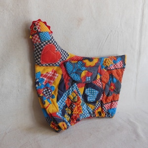 May include: A colorful patchwork fabric chicken with a red heart, blue and yellow flowers, and red and white gingham patterns.