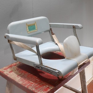 May include: A light blue vintage Little Tondey potty chair with a white strap and a white plastic back support. The chair is sitting on a red wooden stool.
