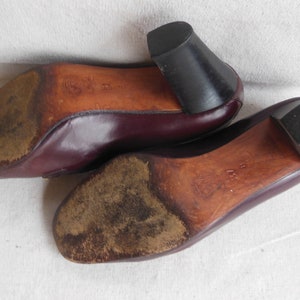 May include: A pair of burgundy leather shoes with a low heel. The shoes have a worn leather sole.