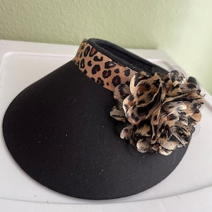 May include: A black sun hat with a leopard print band and a large leopard print flower accent.