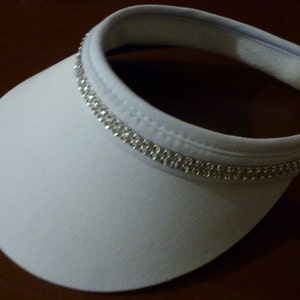 May include: White visor with a row of silver rhinestones around the brim.