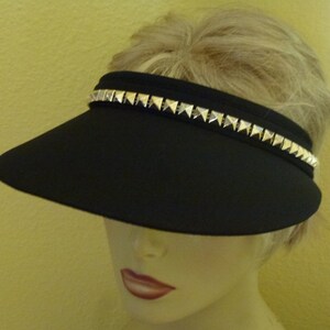 May include: A black visor with a silver studded band around the brim.
