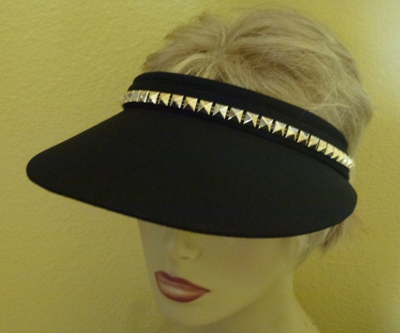 May include: A black visor with a silver studded band around the brim.