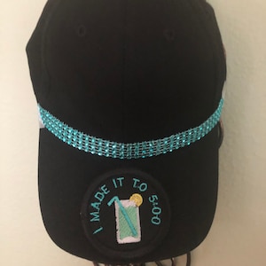 May include: Black baseball cap with a turquoise rhinestone band and a circular patch that says "I made it to 5:00" with a picture of a glass of lemonade with a straw and a lemon slice.