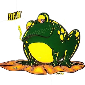 May include: A green frog with yellow spots sits on a brown leaf. The frog has a large, round belly and a small, pointed head. The frog is looking to the right and has a small, white speech bubble above its head that says "RIRET".