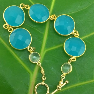 May include: A gold bracelet with turquoise and clear faceted stones. The bracelet has a toggle clasp.