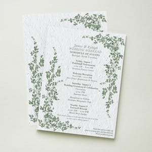 May include: Two white textured paper cards featuring green ivy illustrations. The text reads James & Ryleigh Wedding Weekend Schedule of Events, listing Friday, Saturday, and Sunday activities in Raleigh, North Carolina, with planting instructions.