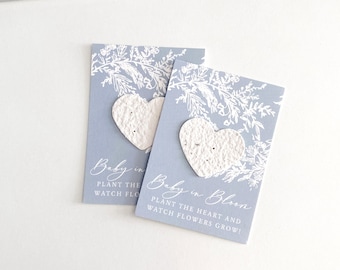 May include: Two blue cards with white floral designs and the text "Baby in Bloom" and "Plant the heart and watch flowers grow!"  Each card has a white heart-shaped seed paper.