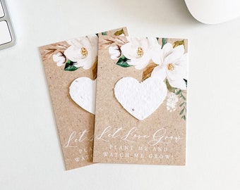 May include: Two brown paper cards with white floral designs and white heart-shaped seed paper. The text on the cards reads "Let Love Grow, Plant Me and Watch Me Grow".