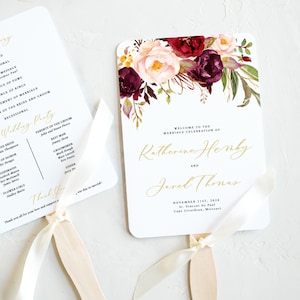 Könnte beinhalten: Ein Hochzeitsfächer mit einem floralen Design in den Farben Burgunderrot, Rosa und Grün. Der Fächer zeigt die Namen Katherine Henby und Jarel Thomas, das Hochzeitsdatum und den Ort der Zeremonie. Der Text "Willkommen zur Hochzeitsfeier von" ist in Gold gedruckt.