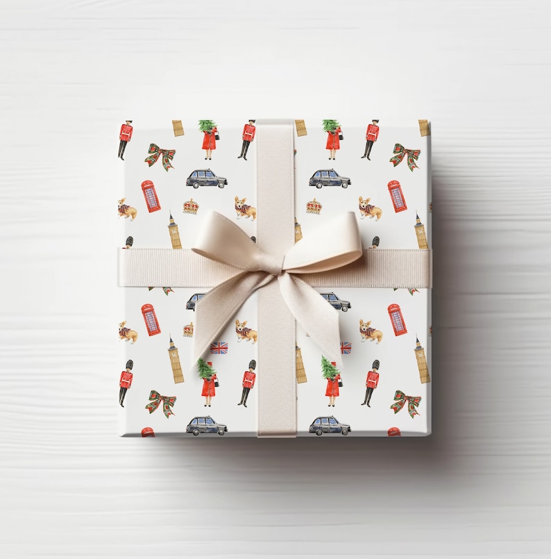 May include: A wrapped gift box with a cream-colored ribbon and bow. The gift wrap features a repeating pattern of British icons, including a red telephone box, a black taxi, a corgi, and a soldier in a red uniform.