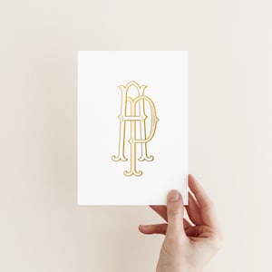 May include: A white card with a gold monogram of the letters "HD" in a decorative font.
