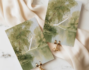 May include: Two rectangular table number cards featuring an impressionistic painting of a green willow tree by a river. The card on the left displays the white number 1, and the card on the right displays the white number 2. Each card is held by a gold stand.