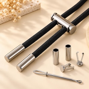 May include: A black braided cord featuring a sliding silver-toned metal toggle and two matching silver-toned metal end caps. Included are two additional silver-toned metal cylinders, two small metal clips, and a thin metal threading tool.