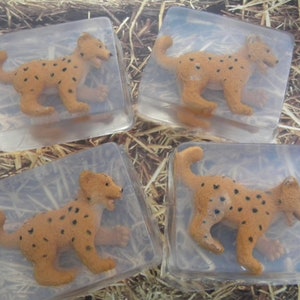 May include: Four clear soap bars with a brown and black cheetah figurine inside each bar. The bars are sitting on a bed of straw.