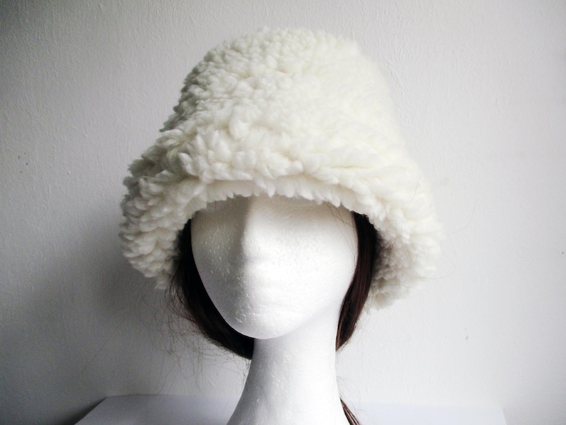 Puede incluir: Un gorro blanco y esponjoso de estilo bucket hecho de piel sint&eacute;tica. El gorro es suave y tiene un ala ancha.
