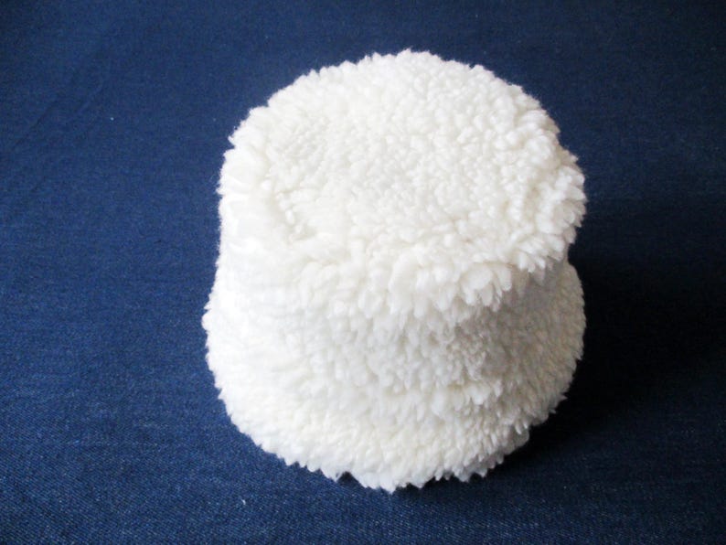 Puede incluir: Un gorro de cubo blanco y peludo. El gorro est&aacute; hecho de un material suave y afelpado.