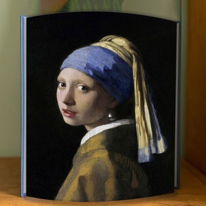 Może przedstawiać: Obraz przedstawiający młodą kobietę w niebiesko-żółtym chustce i z perłową kolczykiem. Ma na sobie brązową i złotą sukienkę. Tło jest ciemne.