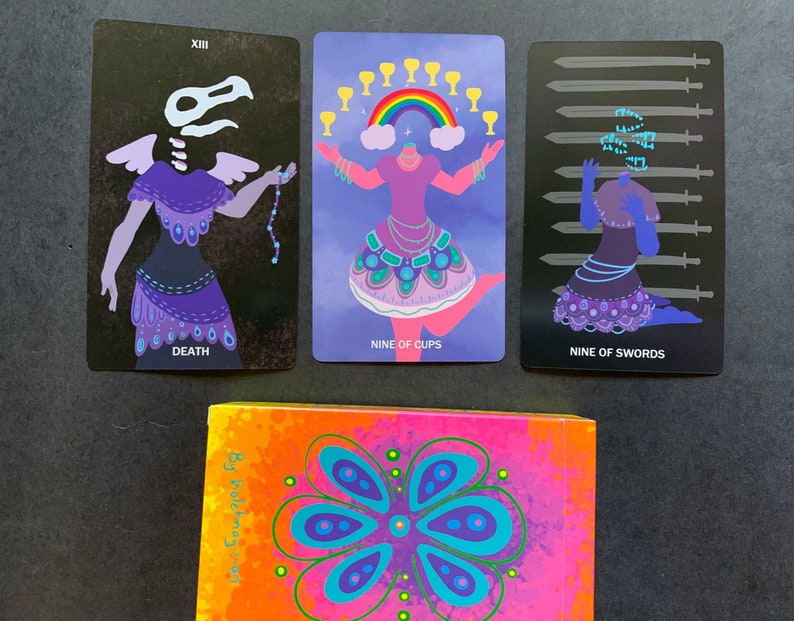Puede incluir: Tres cartas de tarot con fondos negros e ilustraciones coloridas. Las cartas se titulan "Muerte", "Nueve de Copas" y "Nueve de Espadas".