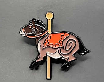 Könnte beinhalten: Ein Emaille-Anstecknadel mit einem Karussellpferd in Braun-, Schwarz- und Orangetönen. Die Anstecknadel zeigt ein detailliertes Design eines Pferdes mit fließender Mähne und einem dekorativen Sattel. Das Pferd ist an einer goldfarbenen Stange befestigt.