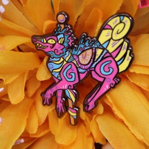 May include: A colorful enamel pin featuring a stylized mythical creature with pink, blue, yellow, and purple details. The pin has a black outline and is set against a bright yellow background.