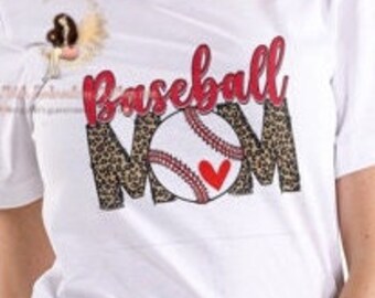May include: White t-shirt with the words "Baseball Mom" in red and leopard print. The design includes a baseball with red heart details. The shirt is short-sleeved and has a crew neck.