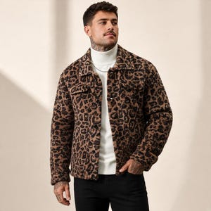 Puede incluir: Una chaqueta con estampado de leopardo en marrón y negro con un acabado texturizado y difuso, que presenta un cuello clásico, mangas largas y dos bolsillos en el pecho con solapas. La chaqueta se lleva sobre un suéter de cuello alto blanco y pantalones negros.