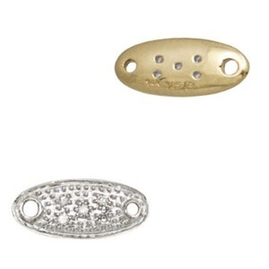May include: Two oval-shaped jewelry findings. One is gold-toned with six small holes and two larger holes. The other is silver-toned and covered in small, sparkling stones, also with two larger holes for attachment. Jewelry components.
