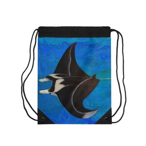 May include: A black drawstring backpack featuring a graphic print of a manta ray swimming through deep blue water. The bag has black fabric at the top and bottom corners, with black cord straps for closure and carrying on the shoulders.