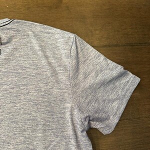 May include: A pale blue short-sleeved shirt with a textured pattern. The shirt has a crew neck and a simple design. The fabric appears to be a lightweight, breathable material.