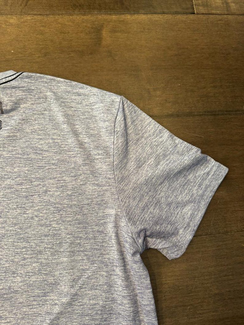 May include: A pale blue short-sleeved shirt with a textured pattern. The shirt has a crew neck and a simple design. The fabric appears to be a lightweight, breathable material.