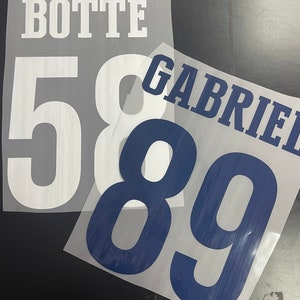 Puede incluir: Dos transferencias de planchado blancas con el texto "BOTTE" y los n&uacute;meros "58" en una transferencia y el texto "GABRIEL" y los n&uacute;meros "89" en la otra transferencia.