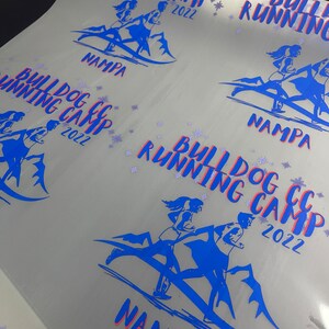 Puede incluir: Una hoja de papel blanca con varios dise&ntilde;os azules y rojos impresos en ella. Los dise&ntilde;os muestran a un grupo de personas corriendo en una monta&ntilde;a con el texto "Bulldog CC Running Camp 2022" y "Nampa" impreso debajo.