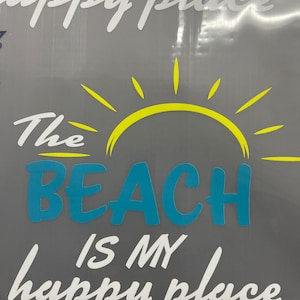Pu&ograve; includere: Una grafica bianca su sfondo grigio con un sole giallo e il testo "The Beach is my happy place".