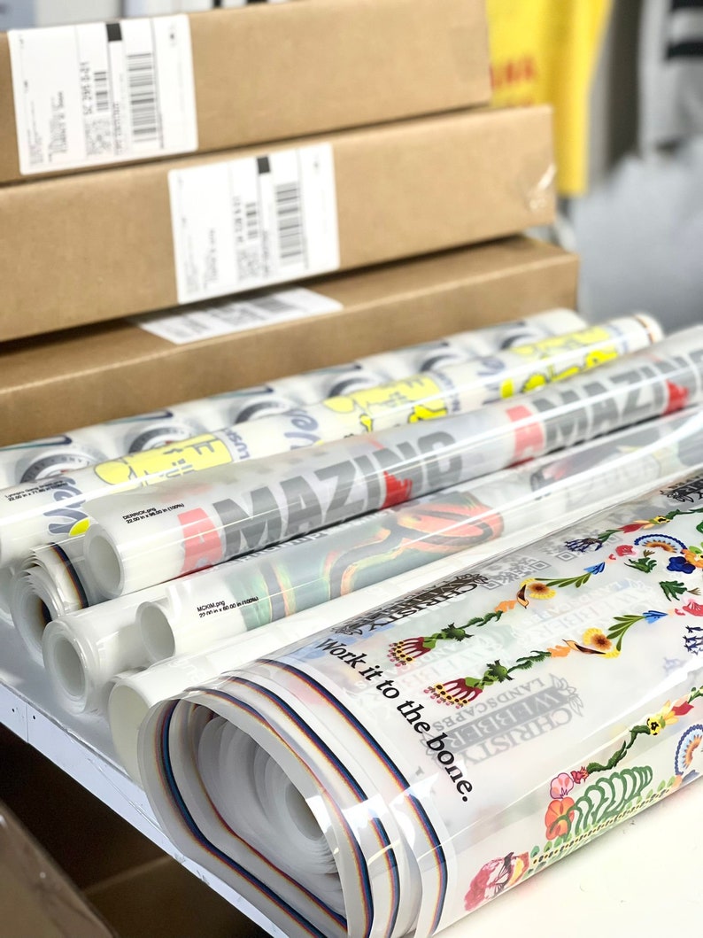 Puede incluir: Un rollo de papel de regalo con dise&ntilde;os coloridos y texto. Los dise&ntilde;os incluyen un arco&iacute;ris, flores y el texto "Work it to the bone."