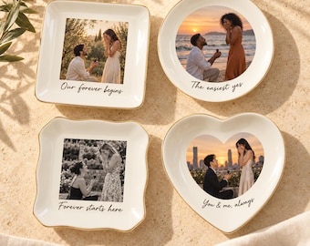 Puede incluir: Cuatro platos de cerámica blanca con bordes dorados, cada uno con una foto personalizada de una propuesta de matrimonio y texto impreso. Los platos son cuadrados, redondos, cuadrados con bordes ondulados y en forma de corazón, con las frases Our forever begins, The easiest yes, Forever starts here y You & me, always.