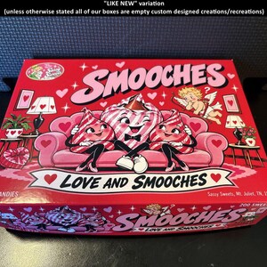 May include: A rectangular red candy box labeled SMOOCHES LOVE AND SMOOCHES. The box features a cartoon illustration of three anthropomorphic candy kisses sitting on a pink sofa, with a cupid figure, lamps, and heart motifs. Text includes 200 CANDIES and Sassy Sweets, Mt. Juliet, TN, 1960.