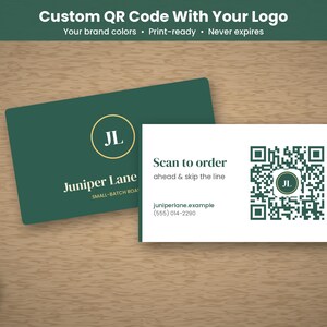 May include: Two rectangular business cards. One is dark green with a gold circular logo featuring the letters JL and the text Juniper Lane. The other is white with a dark green QR code, the text Scan to order ahead & skip the line, and contact info.