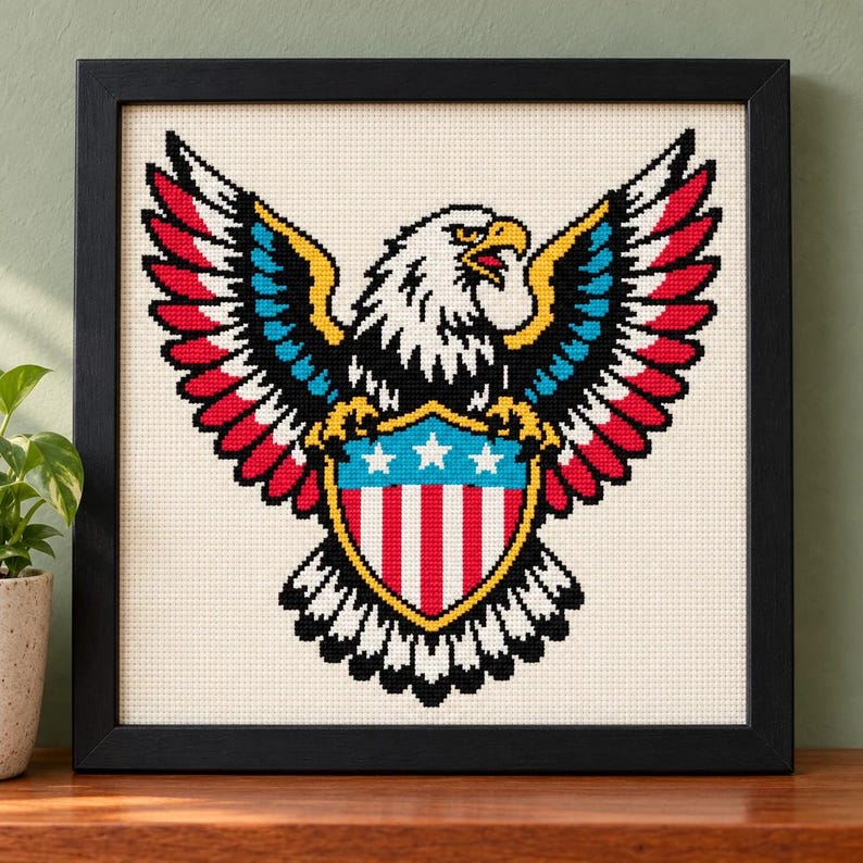 Straight-on view of the finished Eagle and Shield Cross Stitch in a black frame on a wooden shelf