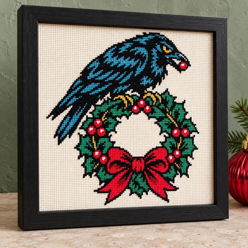 Raven wreath cross stitch in a black frame on a shelf