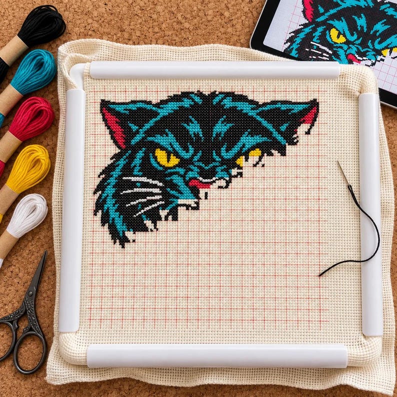 Panther cross stitch in progress in a Q-snap frame with DMC floss, scissors and tablet chart