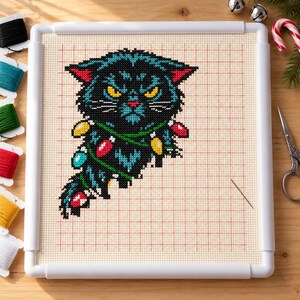 Black cat cross stitch in progress in a Q-snap frame