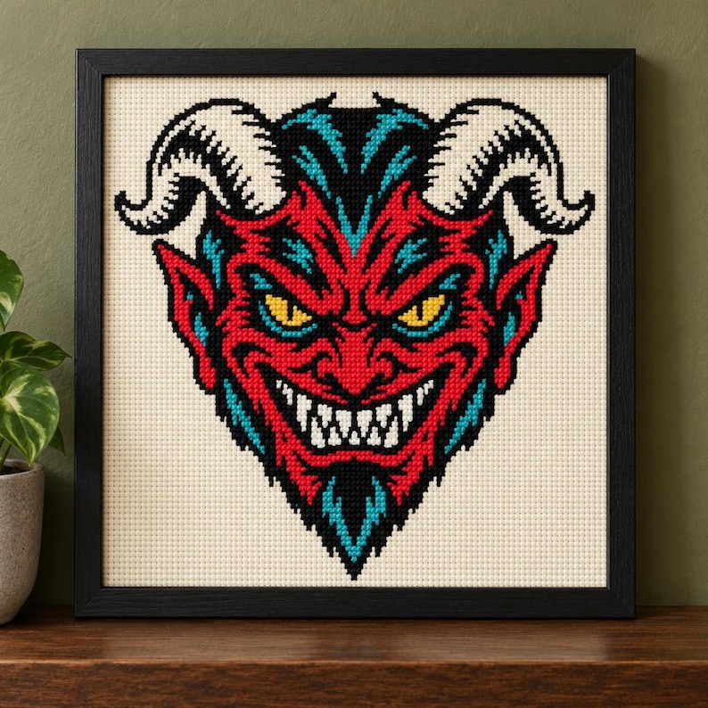 Straight-on view of the finished Devil Cross Stitch in a black frame on a wooden shelf