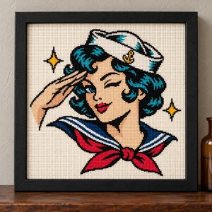 Straight-on view of the finished Sailor Girl Cross Stitch in a black frame on a wooden shelf