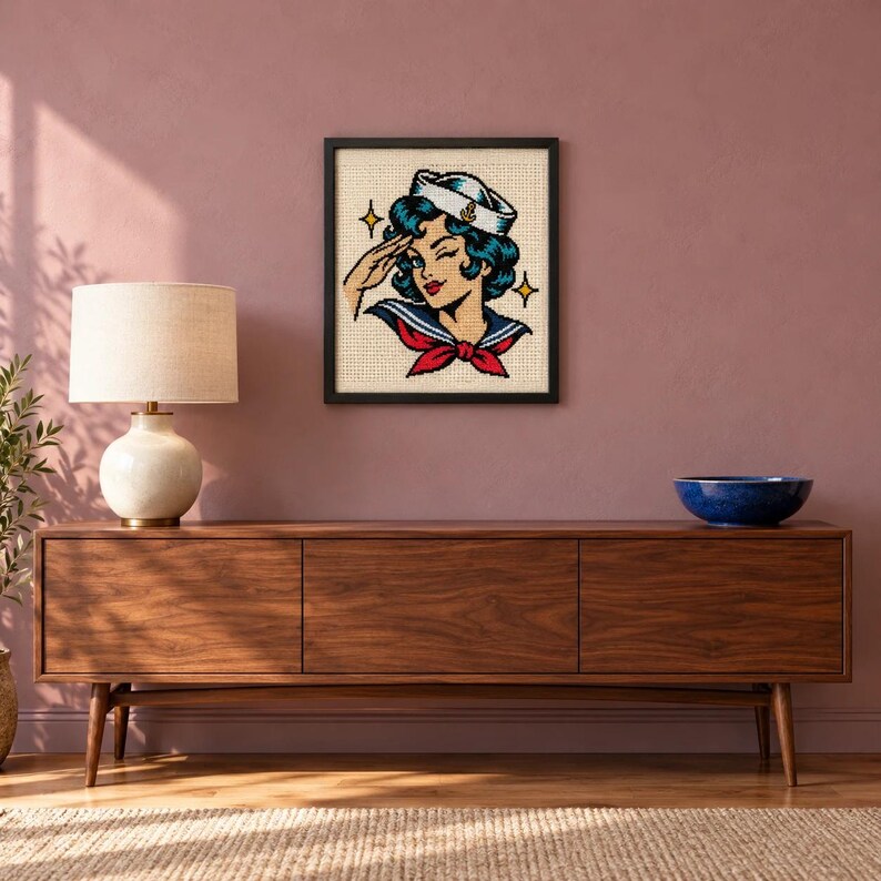 Framed sailor girl tattoo flash cross stitch on a wall