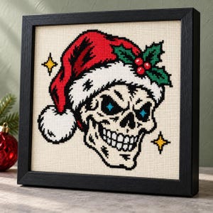 Santa skull cross stitch in a black frame on a shelf