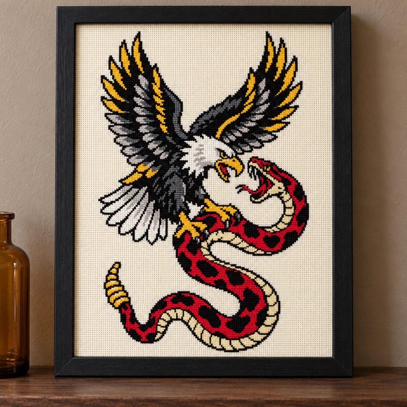 Straight-on view of the finished Eagle and Snake Cross Stitch in a black frame on a wooden shelf