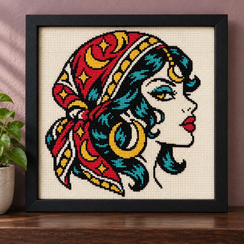 Straight-on view of the finished Fortune Teller Cross Stitch in a black frame on a wooden shelf
