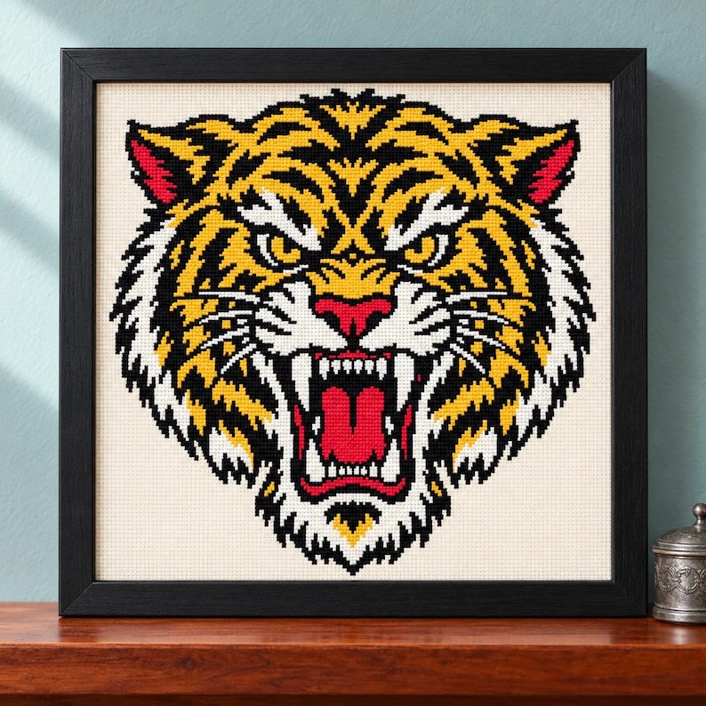 Straight-on view of the finished Tiger Cross Stitch in a black frame on a wooden shelf