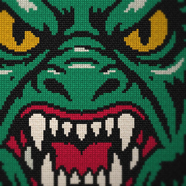 May include: A cross-stitch embroidery pattern featuring a close-up of a green creature's face with yellow eyes, a black nose, and a wide-open mouth revealing sharp white teeth against a dark red interior, all rendered in a pixelated style.